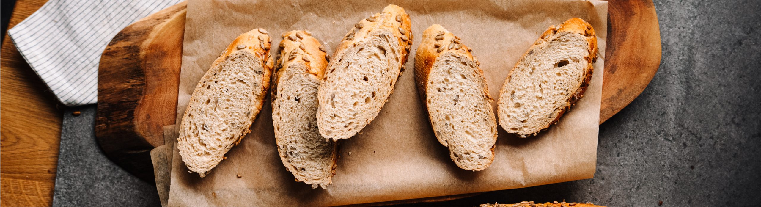 Scheiben eines Baguettes auf Backpapier auf einem Holztablett