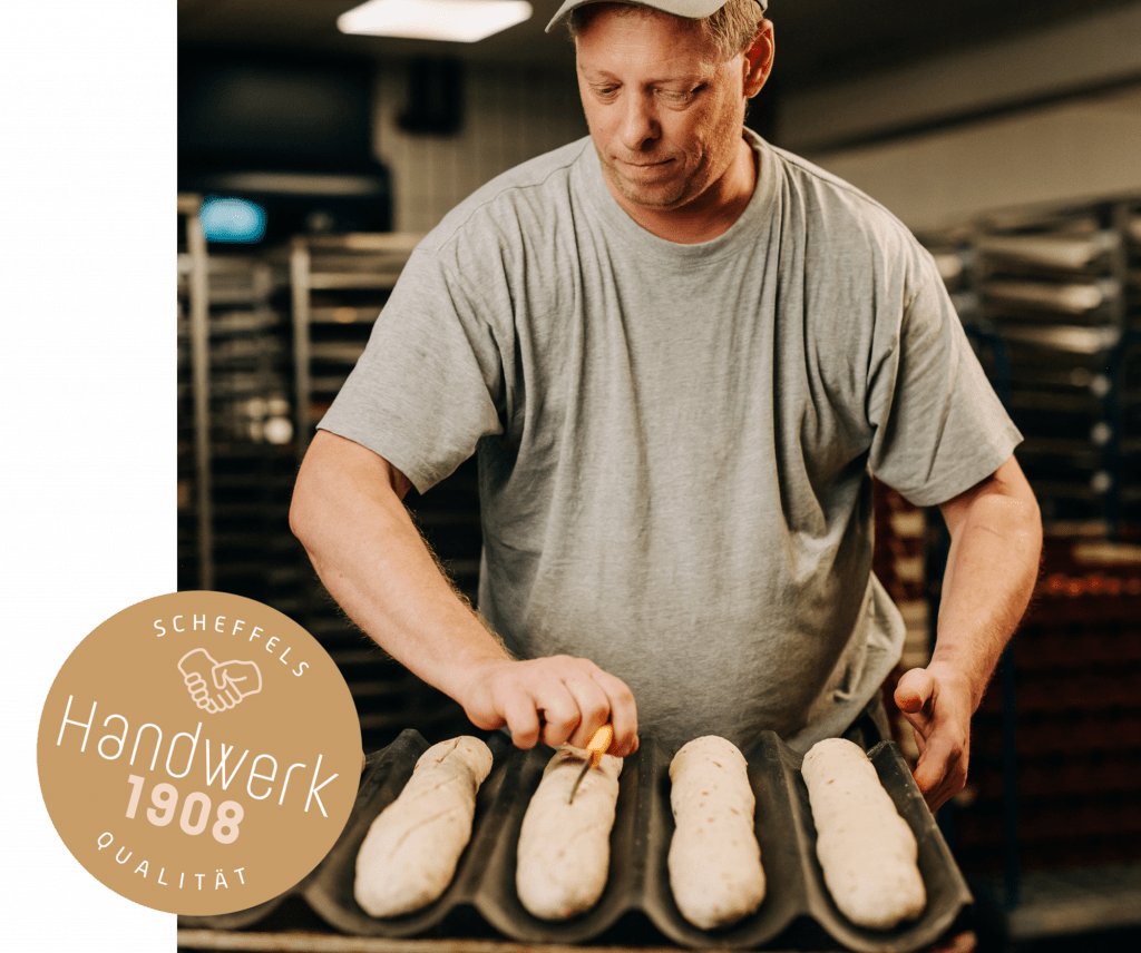 Ein Bild eines Bäckers, der gerade den Brotteig einschneidet und für den weiteren Prozess vorbereitet. Auf der linken Seite befindet sich ein goldener Kreis mit der Aufschrift Scheffels Qualität – Handwerk 1908