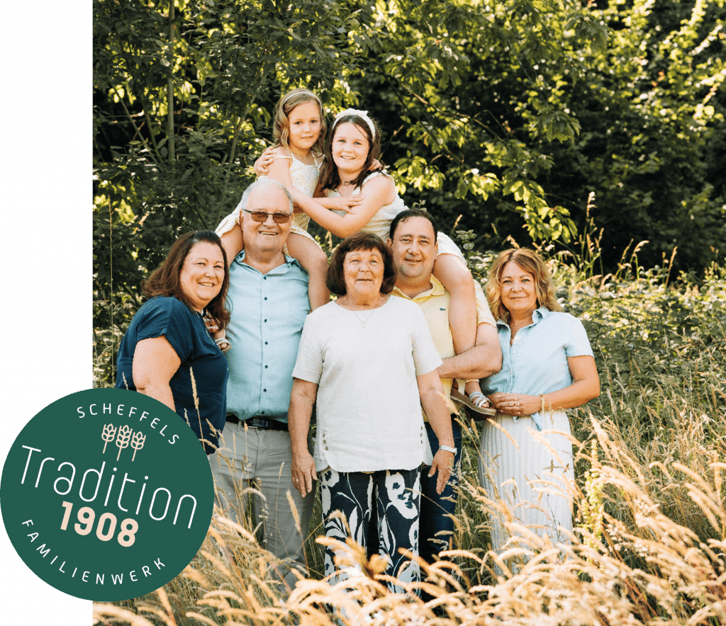 Ein Bild der Familie Scheffel in einer Wald und Feld Kulisse. Auf der linken Seite befindet sich ein Grüner Kreis mit der Aufschrift Scheffels Familienwerk – Tradition 1908